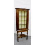 A mahogany corner cabinet with glazed door and shelved interior, raised on turned supports, 180 x