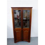 A mahogany bookcase, with a dentil pediment over pair of glazed doors and panelled cupboard doors to