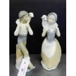 Two NAO Spanish porcelain figures of a boy and a girl, each with a lamb, tallest 26cm, (2)