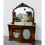 An Edwardian mirror backed chiffonier, the arched mirror surmounted by carved acorn and foliage,