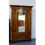 An oak Arts & Crafts wardrobe, the cornice top over a central mirror door over a single long