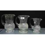 A group of three Edinburgh crystal thistle shaped water jugs of graduating size, un-etched and