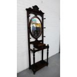 A carved oak hall stand with an oval mirrored plate over a glove box and turned supports, 205 x