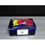 A Moorcroft rectangular box and cover with anemone pattern to a cobalt blue ground with paper