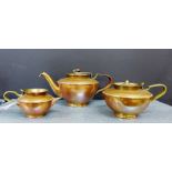 A WMF copper and brass three piece tea set comprising teapot with a raffia bound handle, milk jug