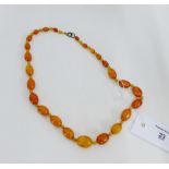A strand of vintage butterscotch amber beads, largest 2cm long, 56cm long overall