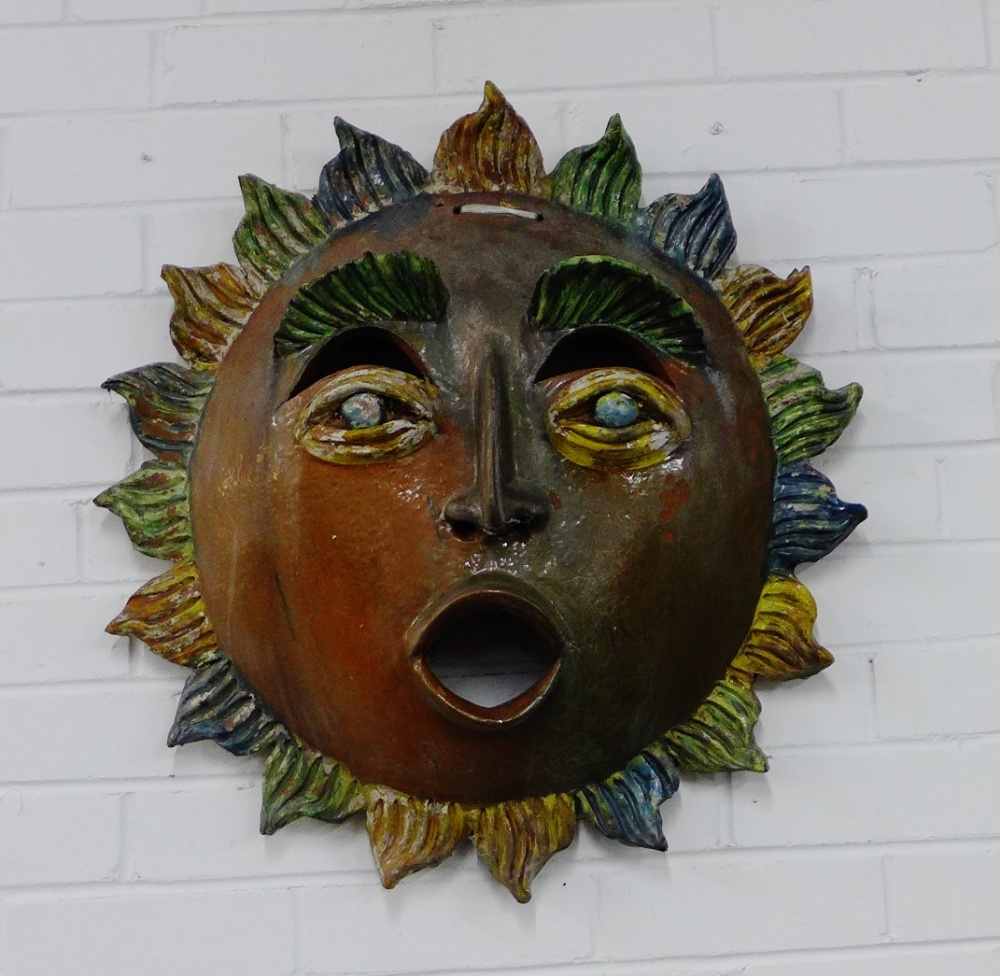 A terracotta painted sun face garden wall ornament, 60cm diameter