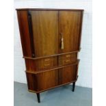 A mid century corner cabinet, the triangular shaped top over a pair of cupboard doors and four short