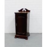 A mahogany bedside cupboard, the square top with a swan neck ledgeback over a panelled door, on