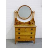 An oak Arts & Crafts dressing table, the circular mirror on pierced supports over a pair of pedestal