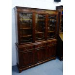 A mahogany bookcase, the cornice top with a dentil frieze over three glazed doors with a shelved