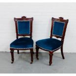 A pair of mahogany framed side chairs each with an architectural top rail, upholstered backs and