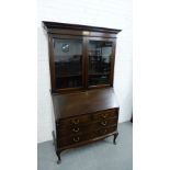 An oak bureau bookcase, the dentil cornice over two glazed doors and a shelved interior, above a