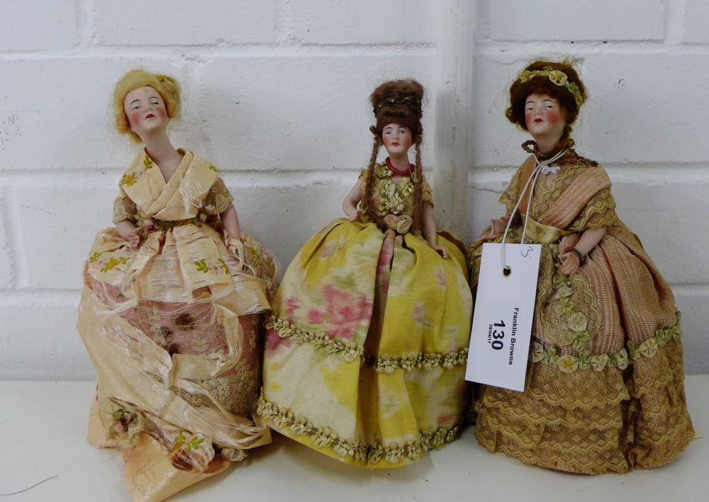 A collection of three bisque half dolls, with blue eyes and blonde wigs, all clothed in crinoline