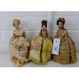 A collection of three bisque half dolls, with blue eyes and blonde wigs, all clothed in crinoline