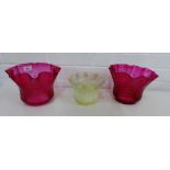 A pair of 19th century cranberry glass frilled rim shades, together with a vaseline glass example,
