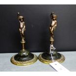 A pair of bronze putti on circular hardstone and brass mounted bases, 19cm high (2)