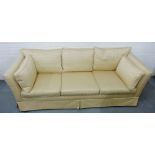 A cream upholstered three seater sofa with loose cushions, 70 x 210cm