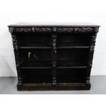 An oak bookcase, the rectangular top with carved edge over mask head frieze and fruit and vine