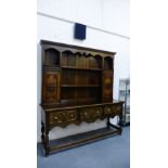 An oak dresser, the cornice top above a planked back with two central shelves, flanked by panelled