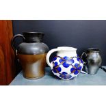 A selection of three jugs to include a stoneware two tone jug, an art pottery floral decorated jug