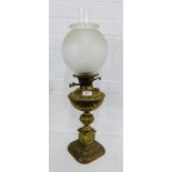 A brass oil lamp with etched glass shade