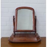 A mahogany dressing mirror with an arched top and raised on bun feet, 50 x 50cm