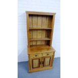 A pine dresser with a planked plate back over two frieze drawers and pair of cupboard doors, on