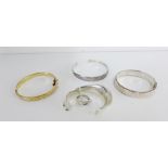 A collection of bangles and cuff bracelets to include a Birmingham silver engraved bangle, a gold