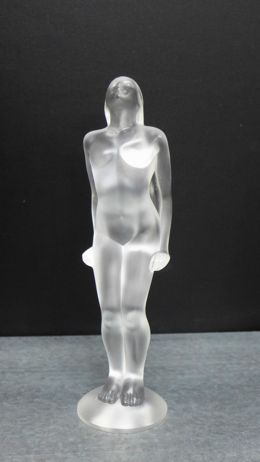 A Lalique glass female nude, modelled standing on a circular base with etched marks to base, 19cm