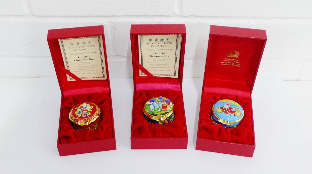 A collection of three Halcyon Days enamel Christmas boxes to include 2002, 2003 and 1999, all in red