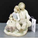 A Lladro porcelain figure group of a boy and a girl with a puppy dog, modelled seated, 16cm high