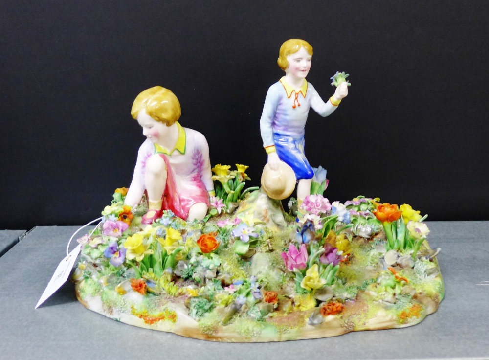 A Crown Staffordshire porcelain figure group modelled by T. Baggaley depicting two girls on a floral