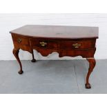 A walnut side table, the bow front top over three drawers and shaped apron, raised on shell carved