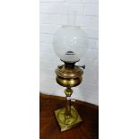 A brass Art Nouveau oil lamp on column support and square base with stylised floral pattern,