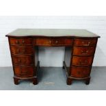 A mahogany kneehole desk, the serpentine top with inset green leather skiver, over one central