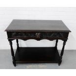 An oak side table, the rectangular top over a leaf and face carved single long drawer, with