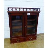 A table top mahogany cabinet, with spindle galleried top over a pair of glazed doors, with a shelved