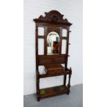 A carved oak hall stand, with arched top over a central mirror back above a glove box, flanked by