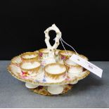 A 19th century porcelain egg cup stand painted with floral sprays and gilded rims, complete with six