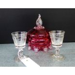 A cranberry glass powder jar and cover, together with two small etched glass liqueur glasses,