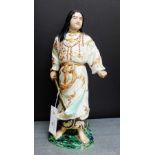 A Japanese earthenware figure dressed in traditional robes with a sword in his hand on an oval