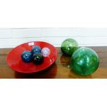 A red lacquered bowl containing a collection of coloured glass fishing floats and balls (a lot)