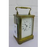 A brass cased carriage clock, the white enamel dial with Roman numerals, size including carry handle