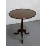 A tilt top table, the circular top with pie crust edge and raised on fluted column and tripod