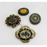 Two Victorian black enamel and yellow metal mourning brooches together with a white metal locket