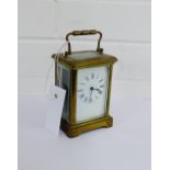 A small brass carriage clock with Roman numerals and carry handle to top, size including handle 15cm