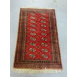 A bokhara style rug, the red field with two rows of ten medallions, 170 x 95cm