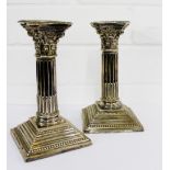 A pair of Edwardian dwarf silver candlesticks, the reeded columns with foliate embossed capitals and