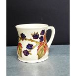 A Moorcroft mug of waisted form with blackberry and leaf pattern with impressed marks to base, 9cm